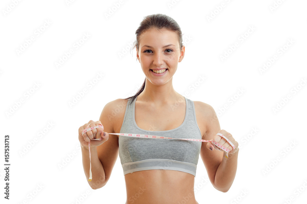 horizontal portrait of a beautiful young girl in a sports tank top that smiling and holding the measuring tape horizontal portrait of a beautiful young girl in a sports tank top that smiling and holding the measuring tape
