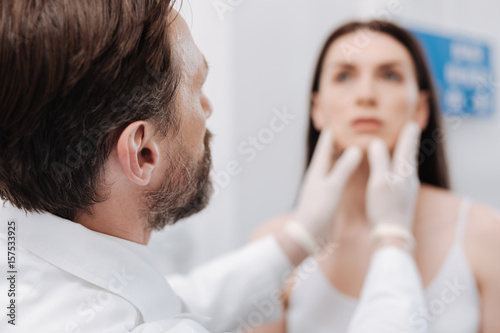 Gentle focused plastic surgeon examining patients face photo