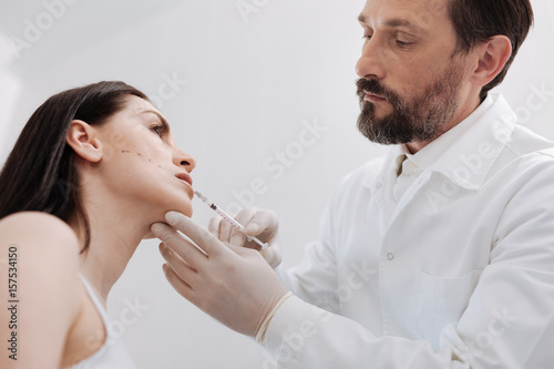 Delicate scrupulous plastic surgeon performing lip augmentation
