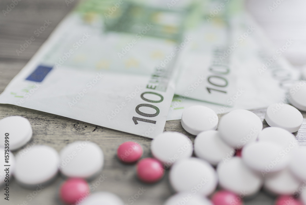 White and pink tablets and money bills White and pink tablets and money bills
