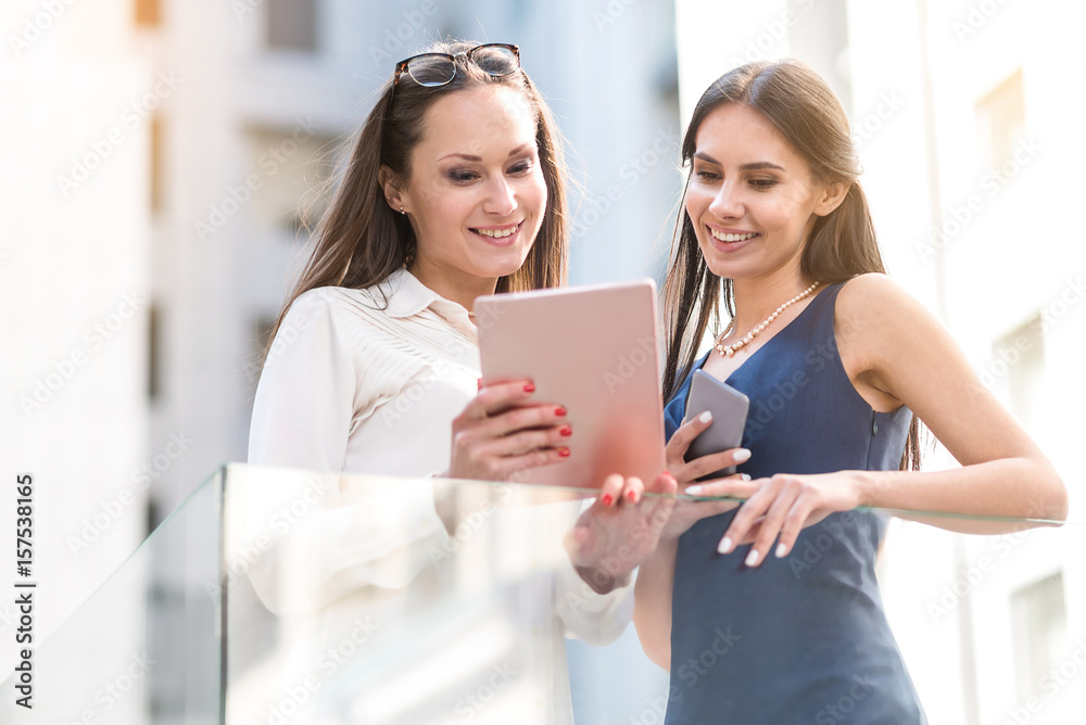 Beaming females watching at electronic tablet Beaming females watching at electronic tablet