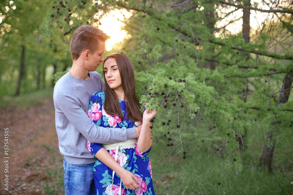 Loving guy and girl in a blooming apple orchard at sunset
