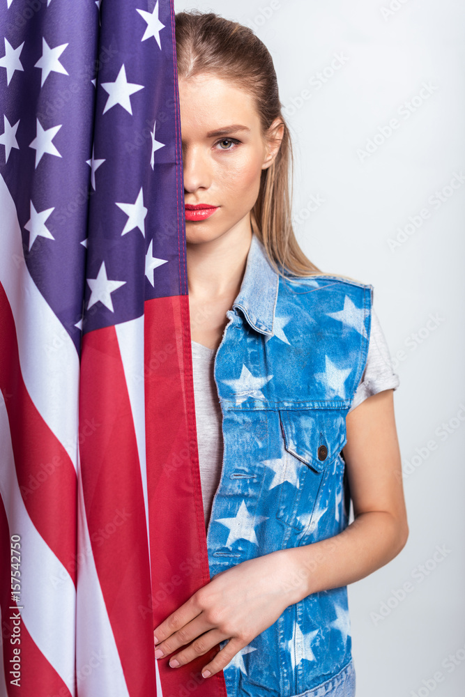 Attractive blonde girl standing with american flag and looking at camera