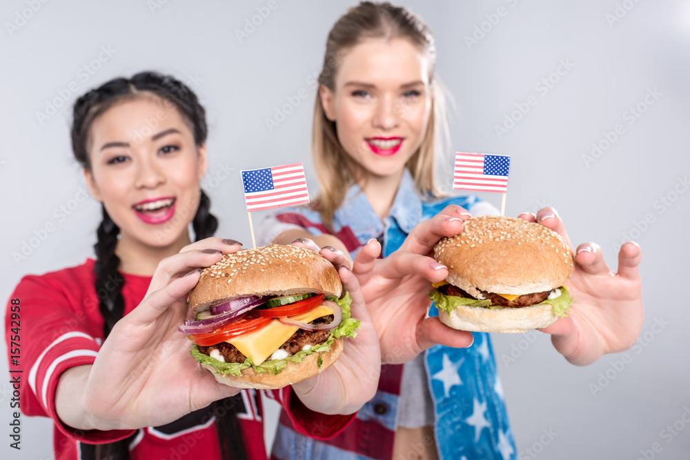 young happy multiethnic women holding burgers with USA flags, Independence Day Celebration