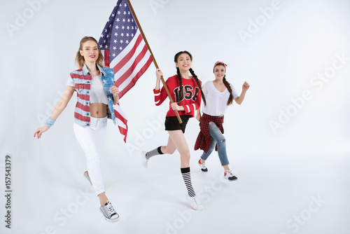 happy young multiethnic women walking with american flag and celebrating 4th july