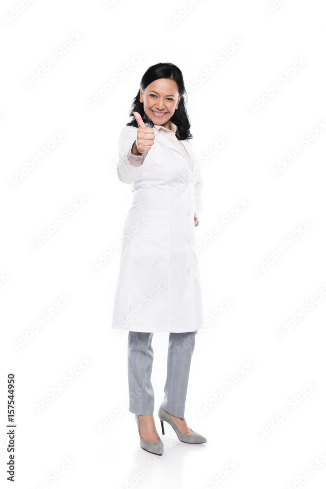 Cheerful brunette woman in white coat showing thumb up and looking at camera Cheerful brunette woman in white coat showing thumb up and looking at camera