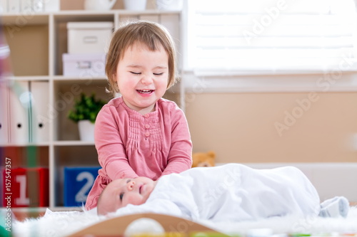Happy toddler girl playing with her baby sister