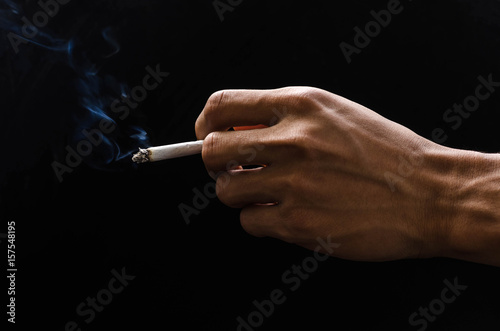 hand holding cigarette and smoke on black