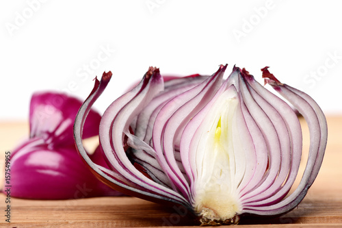Half of red onion with separate slices and pieces behind