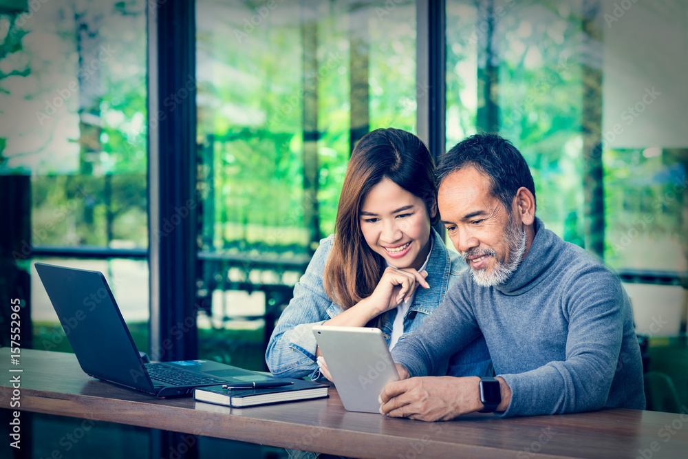 Smiling Attractive mature man with white stylish short beard using tablet with charming woman teenage. Serving internet via his gadget. Teaching old man using social network technology Smiling Attractive mature man with white stylish short beard using tablet with charming woman teenage. Serving internet via his gadget. Teaching old man using social network technology