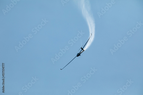 A glider flying in the blue sky ejects the water before the landing.