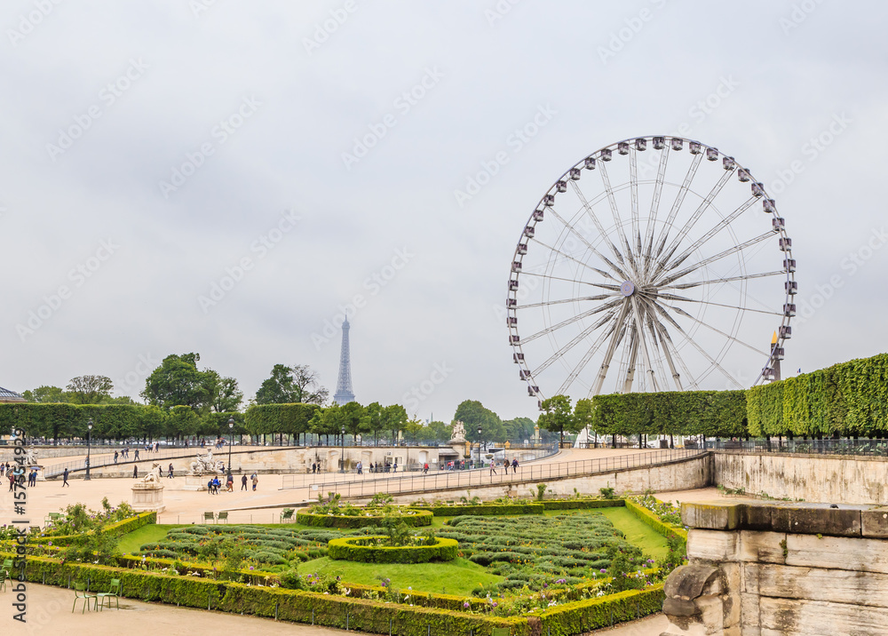  Tourists walk near the Louvre museum on Tuileries park with Ferris wheel on a background