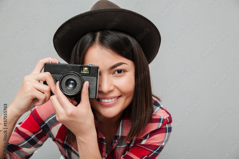 Funny young asian woman isolated over grey wall holding camera. Funny young asian woman isolated over grey wall holding camera.