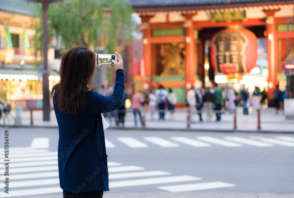 Obraz premium Female asian tourist using smartphone for taking photo of giant lantern in front of Sensoji Shrine (temple), Asakusa, Tokyo, Japan.