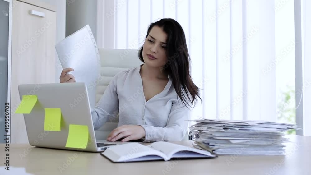 Attractive woman in very hot office trying to cool down with paper Attractive woman in very hot office trying to cool down with paper