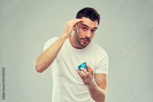 happy young man styling his hair with wax or gel photo