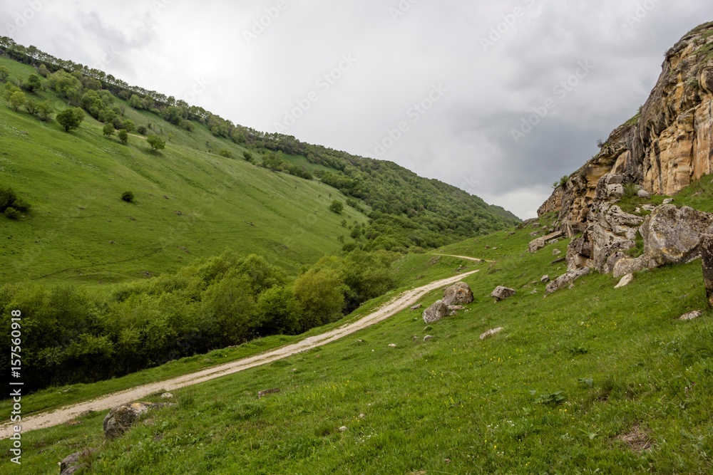 Горная дорога в живописном ущелье между зелеными склонами, горный пейзаж, путешествие по Северному Кавказу