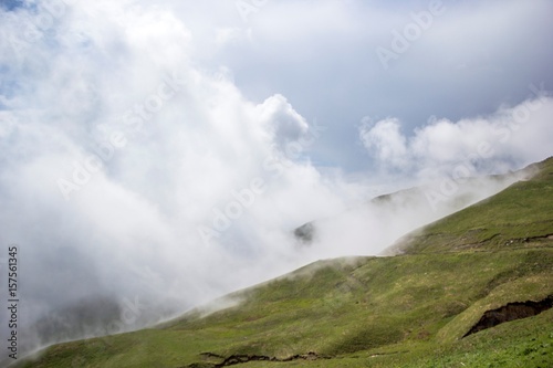 Густой туман, зеленые склоны затянутые белыми облаками, живописный пейзаж