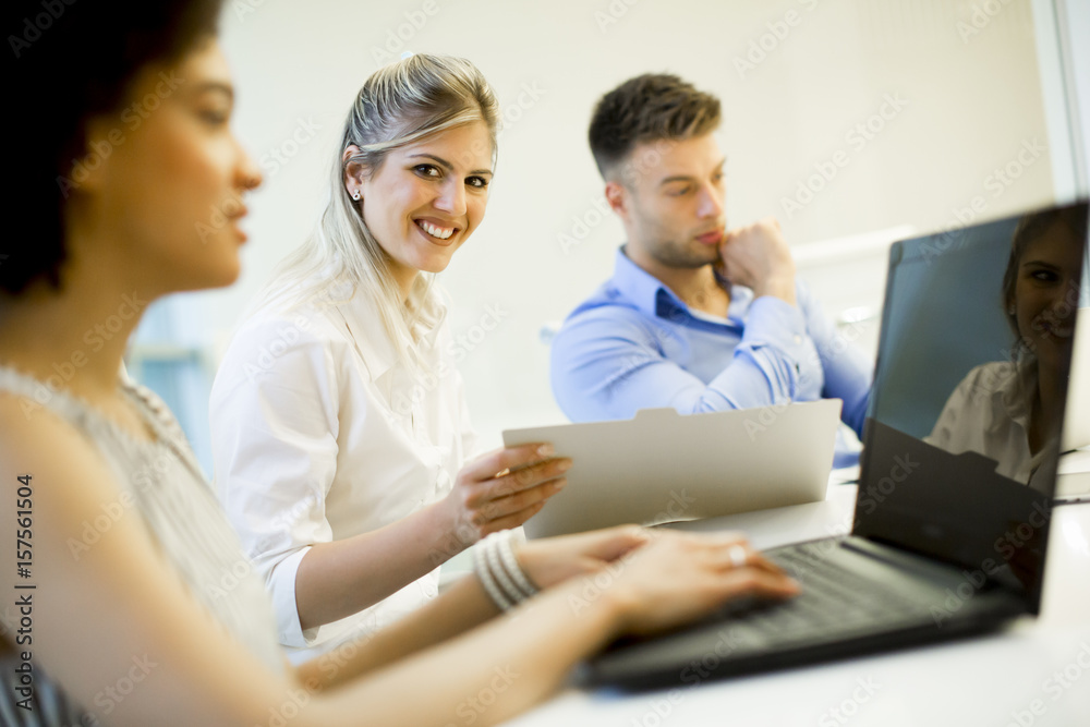 Young business people using laptop and smiling while working in office Young business people using laptop and smiling while working in office