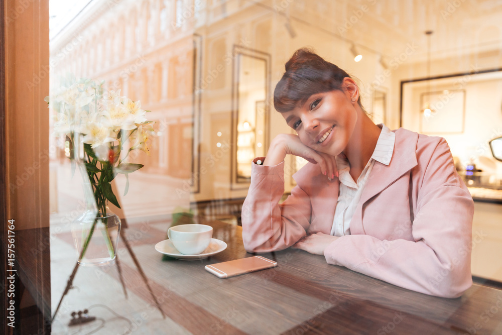 Smiling pretty girl sitting at the cafe table indoors Smiling pretty girl sitting at the cafe table indoors