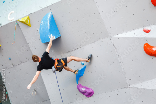 фотографія Male Climber sportsman hanging on artificial Climbing Wall, Competition in diffi