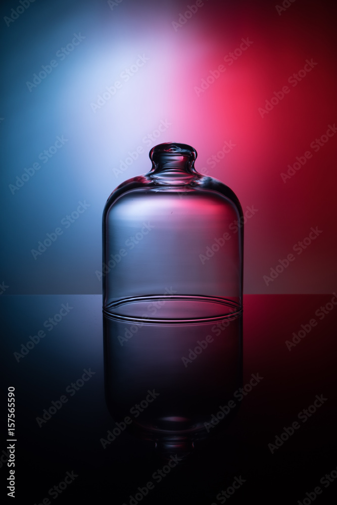 Empty glass jar on a light blue and red background