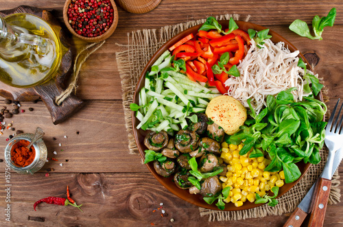 Healthy salad bowl with chicken, mushrooms, corn, cucumbers, sweet pepper and mix salad