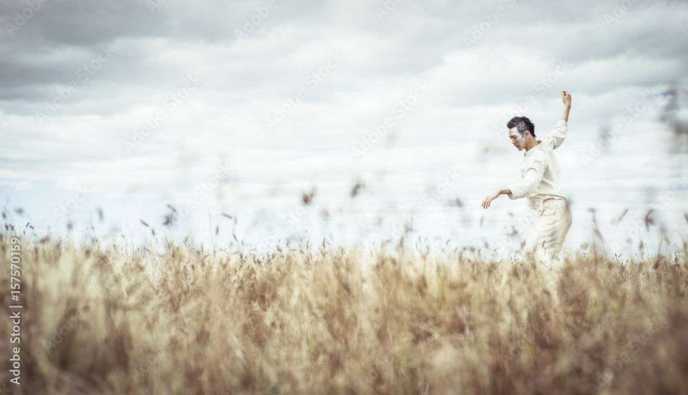 Man with arms outstretched dancing on field against cloudy sky at farm Man with arms outstretched dancing on field against cloudy sky at farm