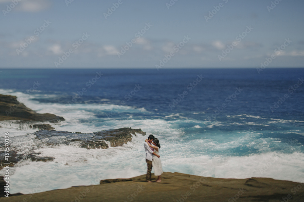 Side view of couple looking at each other while standing at beach against sky Side view of couple looking at each other while standing at beach against sky