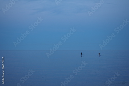 Two girls practicing paddle surf in the middle of the ocean