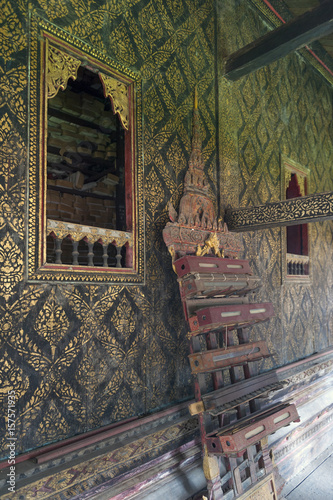Fully Thai-style decorated window and gilded wall, with scripture box on carved wooden shelf inside Ho Trai or the library of Tripitaka (Pali Canon) at Wat Mahathat Temple in Yasothon, Thailandn photo