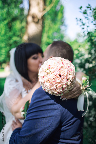 The beautiful wedding bouquet flowers, bride and groom kissing in the background