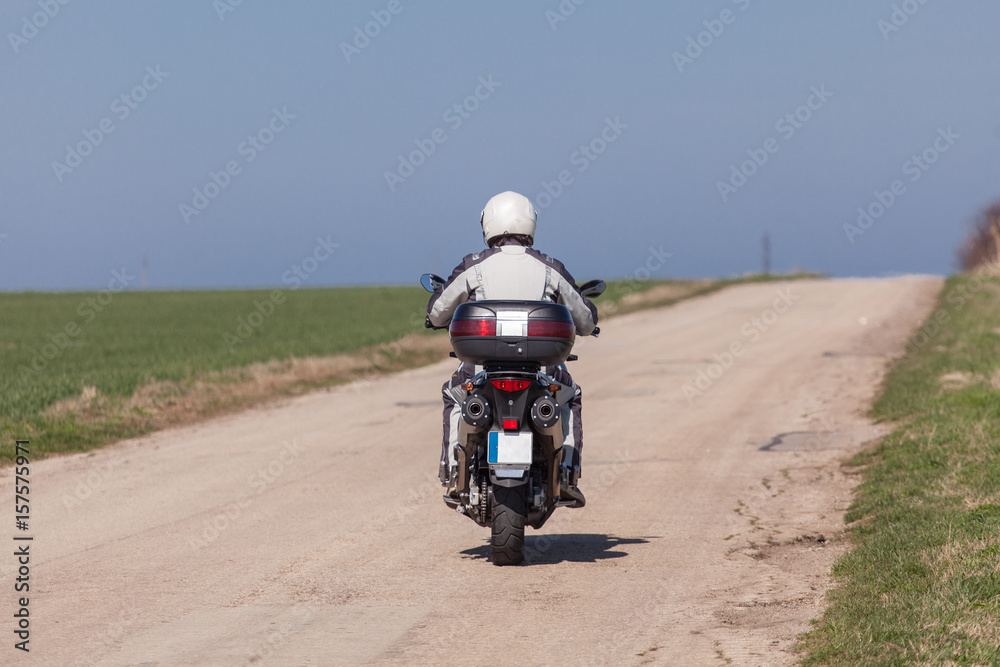 Obraz premium Biker riding on a motorcycle. Driving the empty road on a motorcycle tour journey
