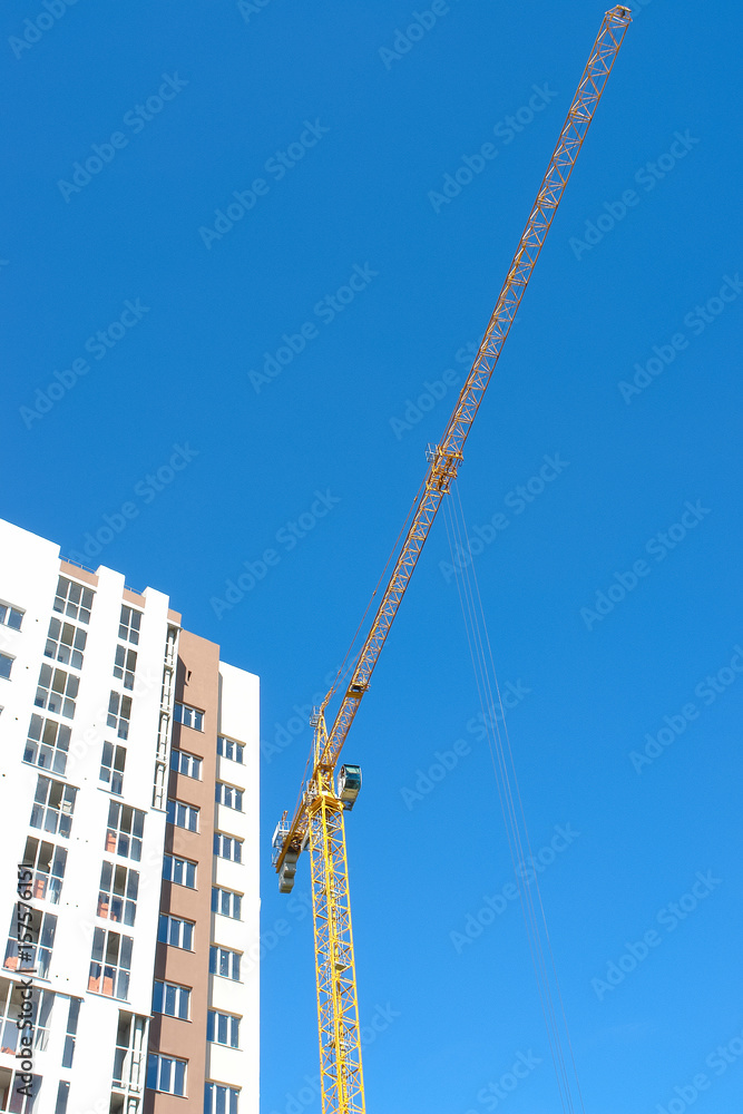 Construction tower crane and new building over blue sky background. Construction tower crane and new building over blue sky background.
