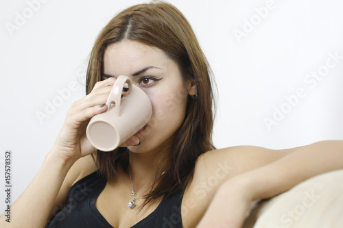 Young attractive woman drinking coffee on sofa