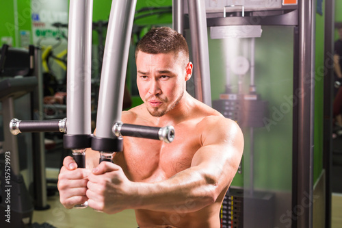 Strong muscular handsome man exercising at the gym