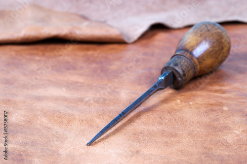 Leather craft tools on a wooden background. Leather craftmans work desk . Piece of hide and working handmade tools on a work table