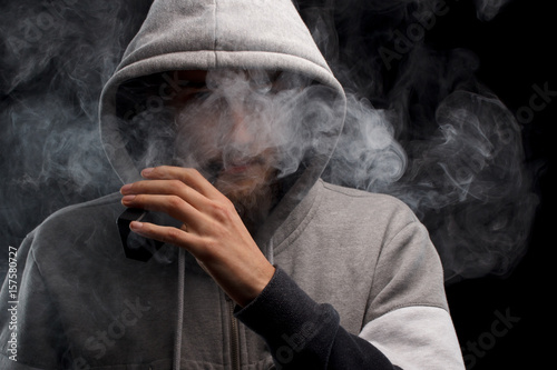 vaping man holding a mod. A cloud of vapor.