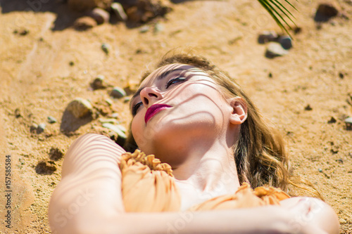 Beautiful woman lying on stones with opened eyes. Very hot sexual girl. Beauty fashion style. photo