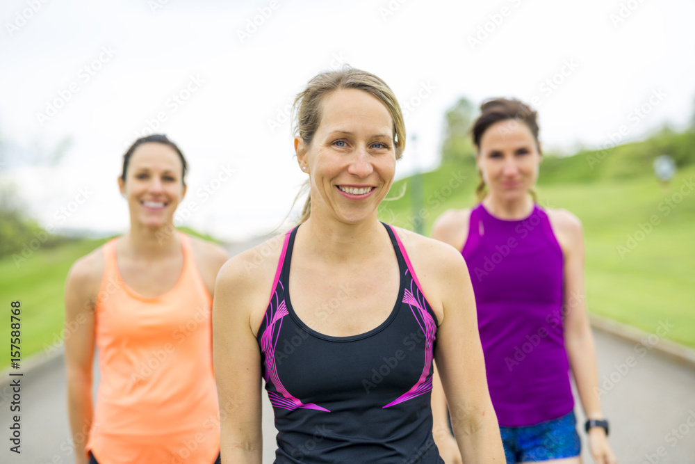 Three relaxed woman runners on a paved jogging daylight