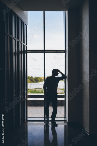 Silhouette of a pensive man near a window. Thoughts, sadness