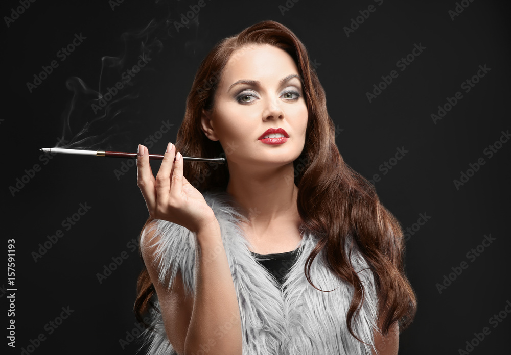 Obraz premium Beautiful woman smoking cigar on dark background