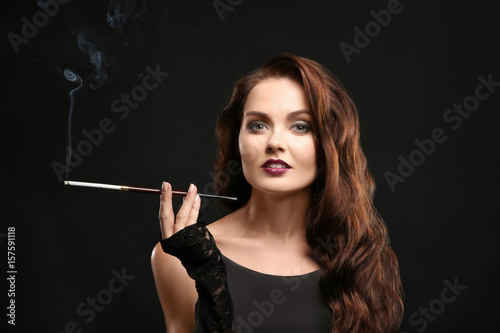 Beautiful woman smoking cigar on dark background