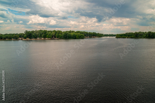 Natural background, lake or river, forest and sky with clouds, on the whole frame. Horizontal frame