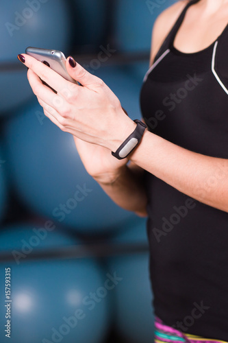 Close-up of female hands with fitness tracker and smartphone in gym