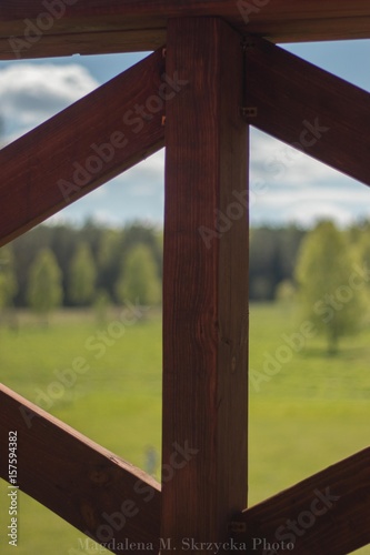 wooden crash barier with green field and forest background