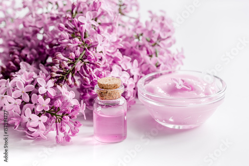 spa cosmetic set with lilac flowers white desk background