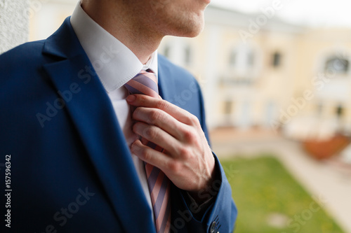 Elegant businessman blue suit, straightens his tie in an expensive hotel, going to a meeting