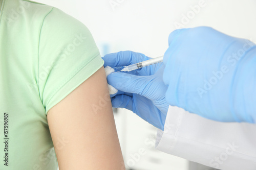 Young woman receiving injection from medical assistant in clinic  closeup