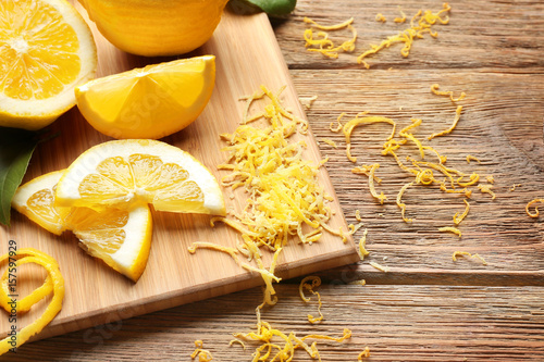 фотографія Board with cut lemons and zest on wooden table, closeup